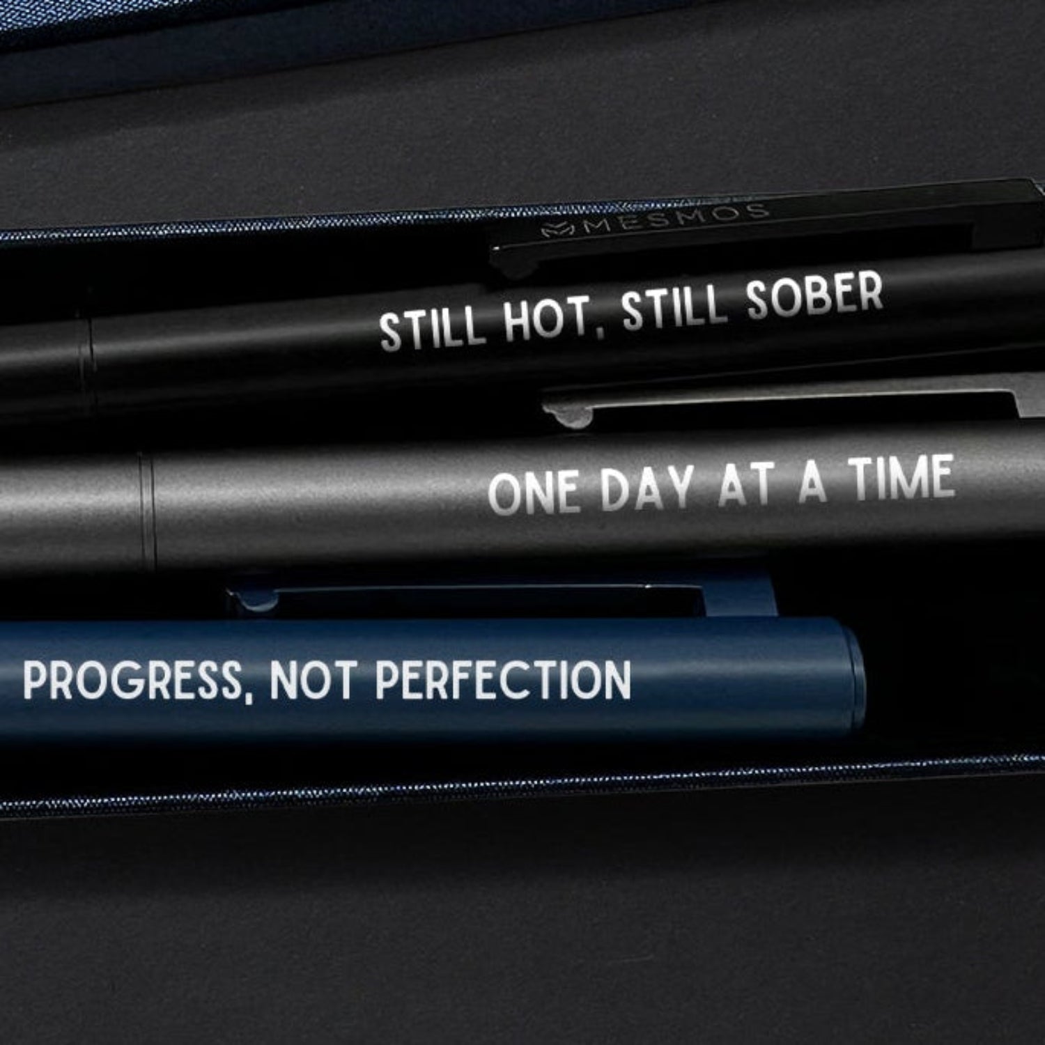 Three motivational pens with engraved text on a dark background-2