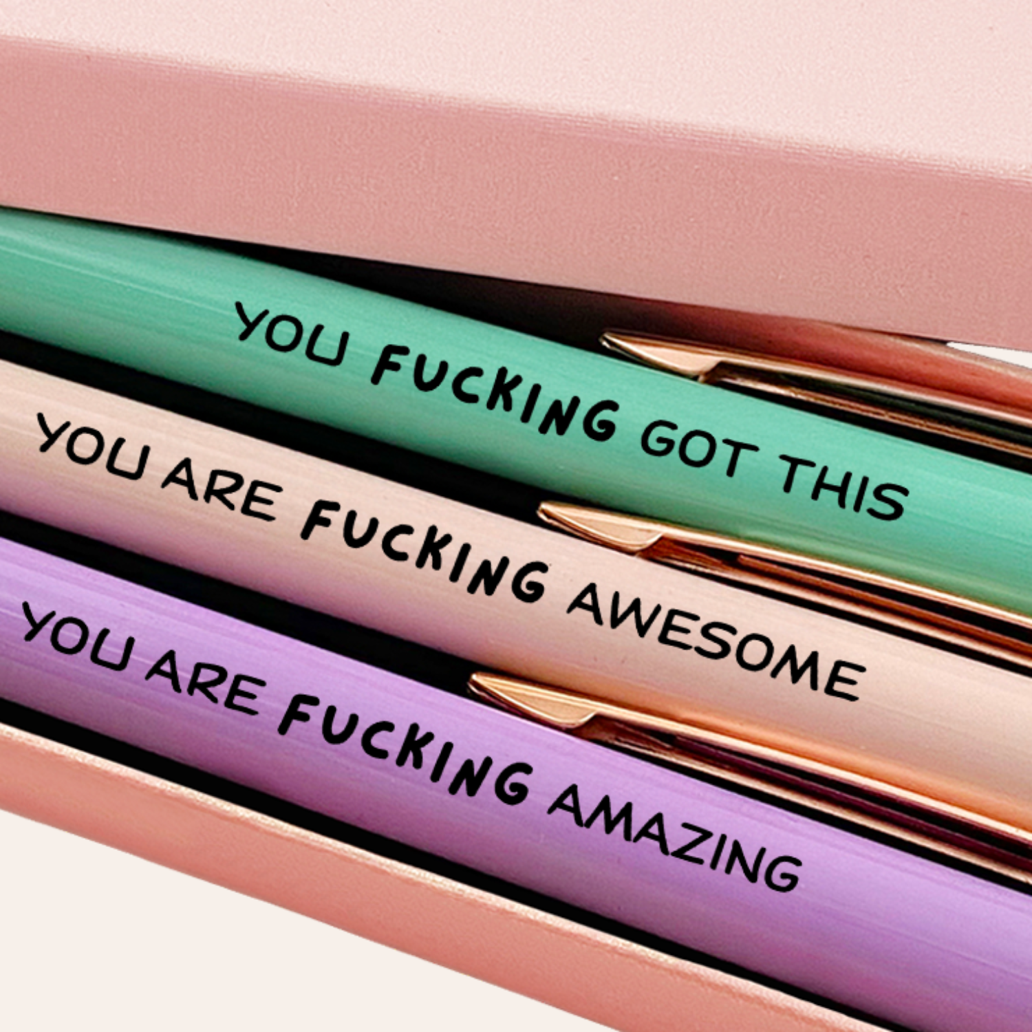 Three pens with motivational phrases in a pink box, featuring the brand 'MESMOS'.-2
