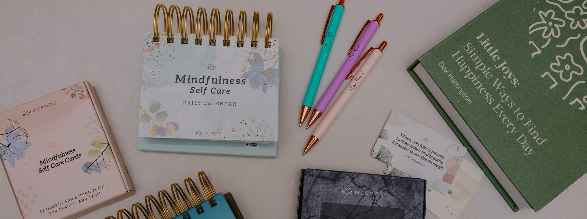 Assorted stationery items including a spiral-bound notebook, pens, and cards on a light surface.