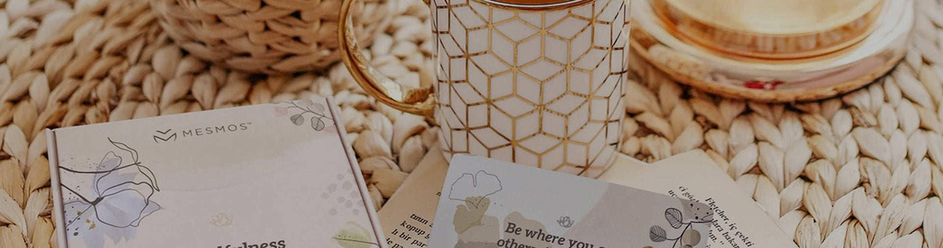 Mesmos wellness cards and inspirational stationery arranged beside a coffee mug on a woven table mat