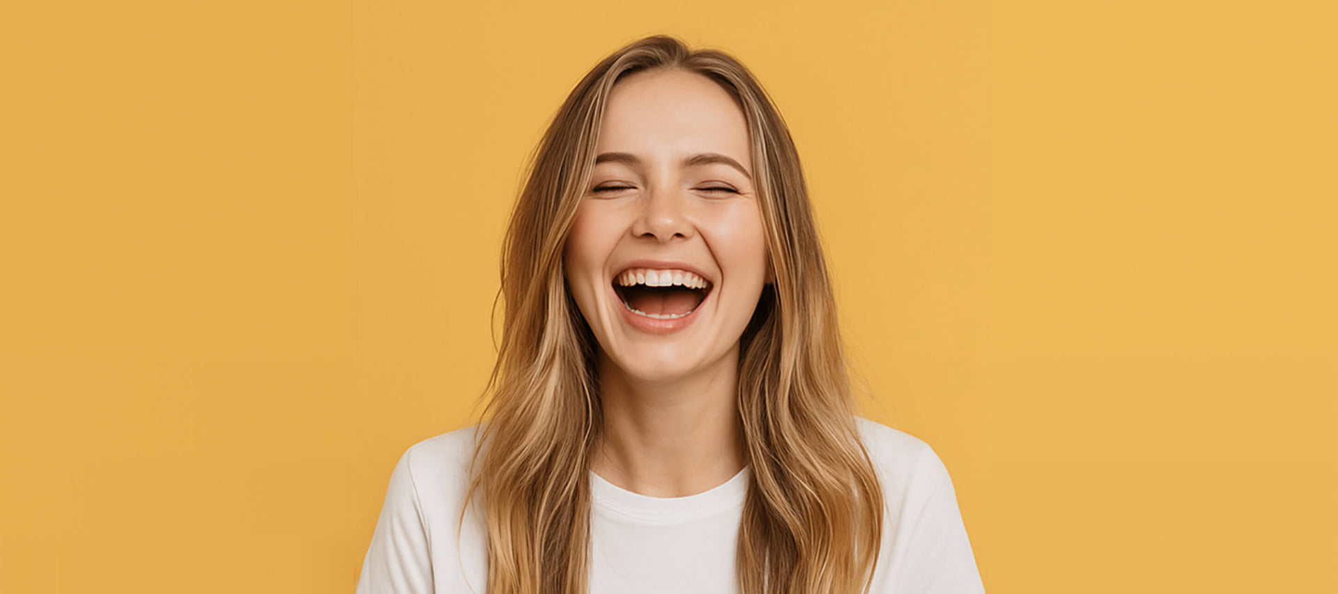 Woman laughing joyfully against a mustard yellow background